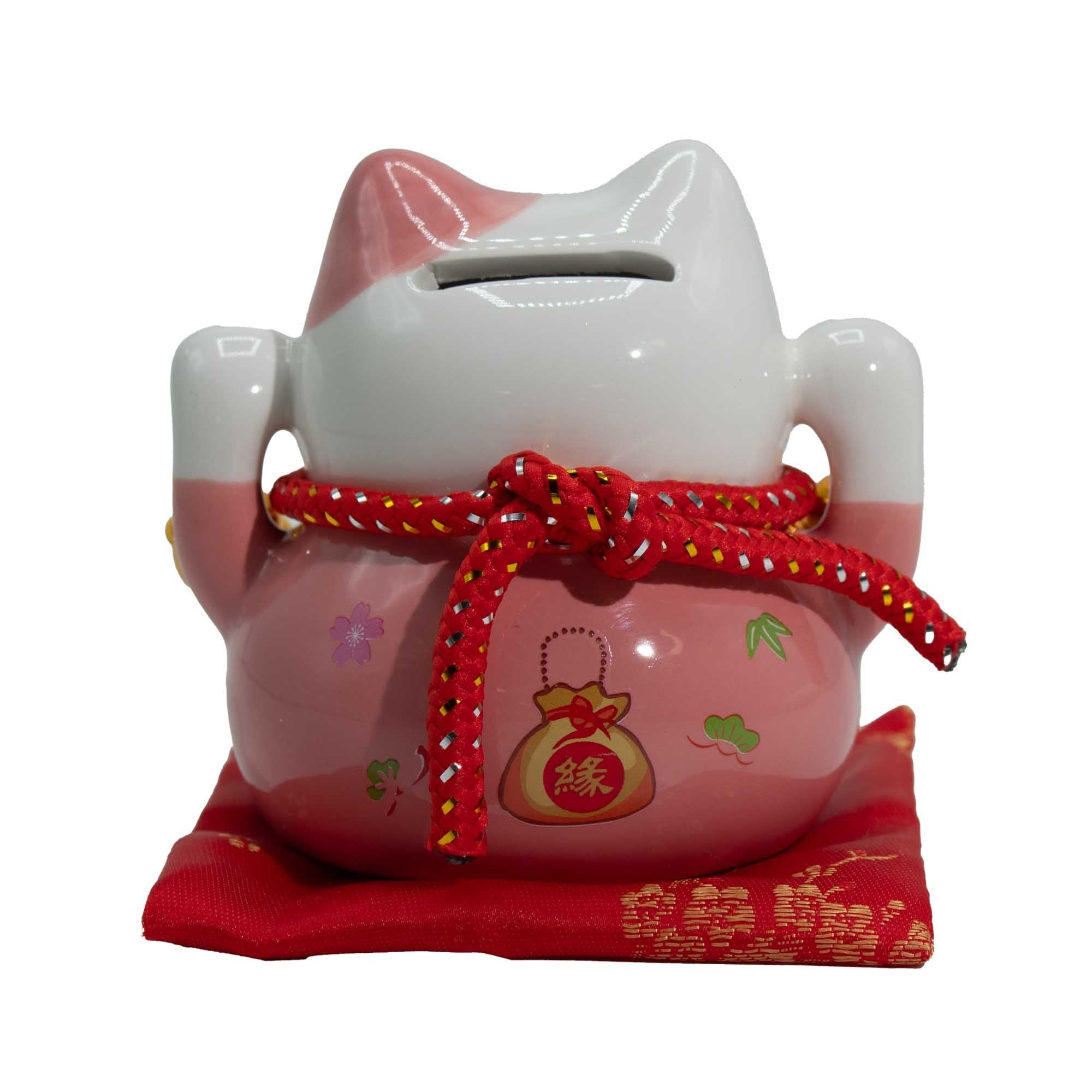 Tirelire porte-bonheur en céramique en forme de chat - rose sur un coussin